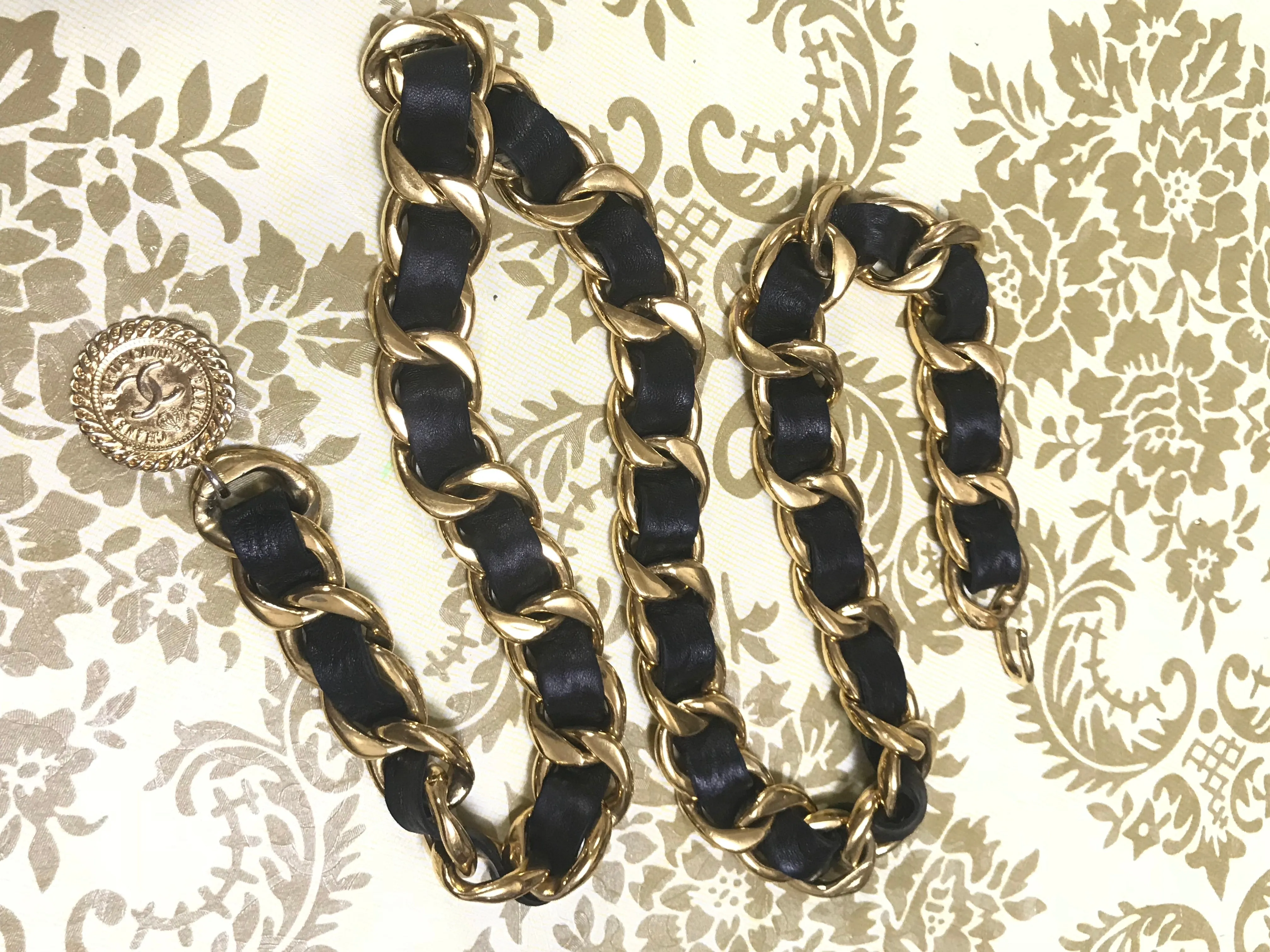 1980s Vintage CHANEL black leather thick chain belt with golden CC and mademoiselle charm. Nice and heavy single layer belt from CHANEL.