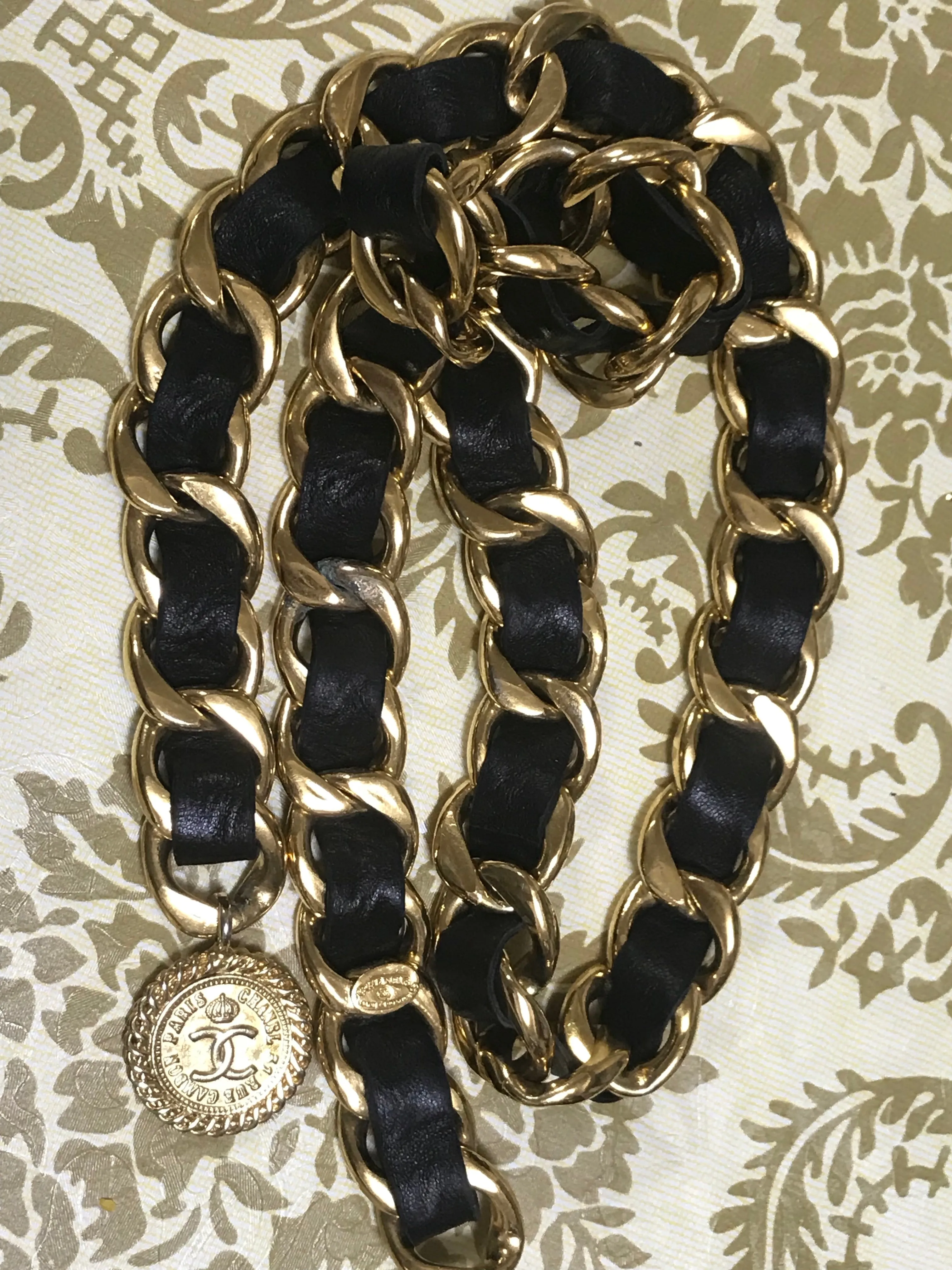 1980s Vintage CHANEL black leather thick chain belt with golden CC and mademoiselle charm. Nice and heavy single layer belt from CHANEL.